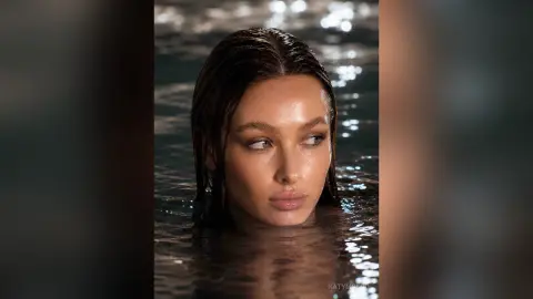 KatyMonro poses with wet hair while partially submerged in dark, shimmering water, looking off to the side.