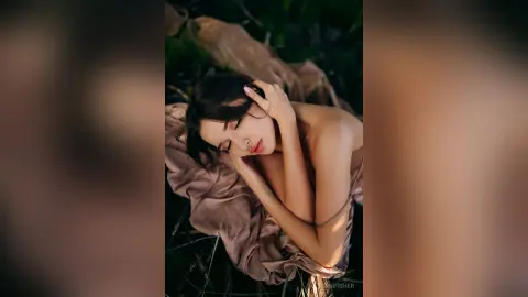 Dreamy portrait of a woman in a flowing beige dress resting peacefully in a lush green meadow.