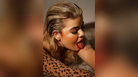 FiorellaRossi licks her lips with her tongue out while wearing a leopard print top.