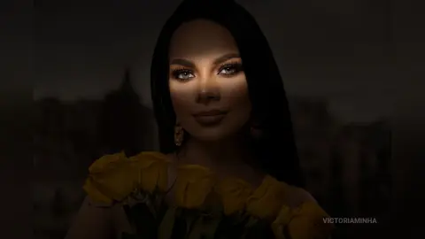 Elegant woman with long dark hair holding yellow roses in moody, cinematic low light.
