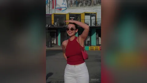 EmmyLee — EmmyLee smiles in a red halter top and white pants while wearing sunglasses outdoors.