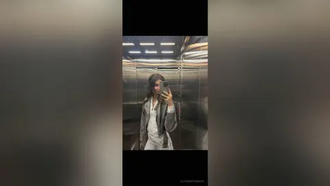 CatherineThomase — CatherineThomase takes a mirror selfie in an elevator wearing a grey jacket and white top.