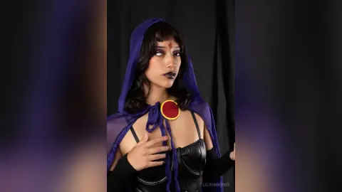 LilithBrooks wears a purple hooded cape and black leather top against a dark background.