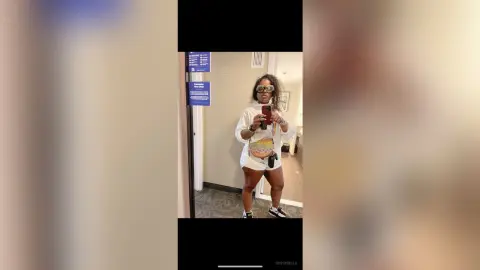 BossyBella — BossyBella takes a mirror selfie wearing a white t-shirt and white shorts, accessorized with dark sunglasses.