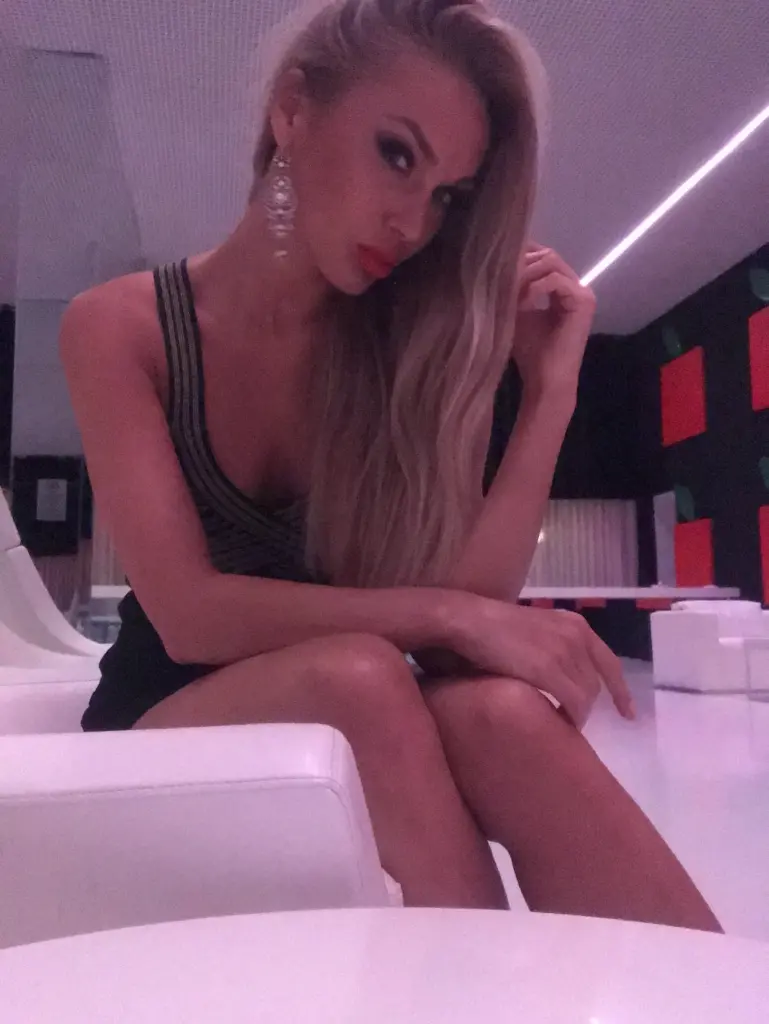 Tina_a poses with her blonde hair swept back, looking directly at the camera with a pouty expression.