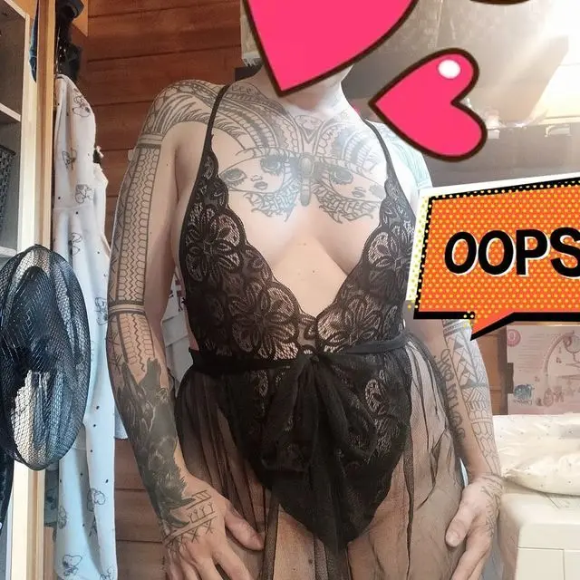 Maitresselexa poses with her blonde hair framing her face, showing off her neck and shoulder tattoos while wearing a black tank top.