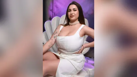 BettyBlossom — BettyBlossom sits on a seashell chair wearing a tight white tank top and matching skirt.