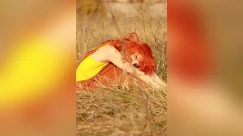 Redheaded woman in a yellow summer dress relaxing in a sunlit autumn field with a dreamy, warm mood.
