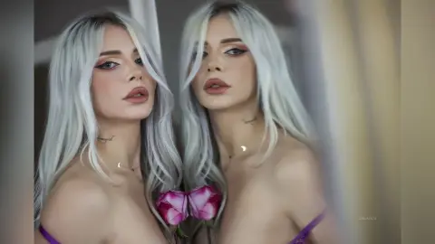 Young woman with long silver hair and glamorous makeup posing in a soft, dreamy aesthetic.