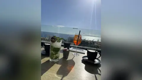 Refreshing mojito and orange cocktail on a sunny seaside balcony overlooking the ocean view.