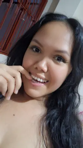 Smiling young woman with long dark hair posing for a close-up portrait in a bright indoor setting.