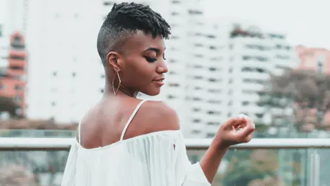 AnnPrice looks over her shoulder wearing a white off-the-shoulder top with her short dark hair styled up.