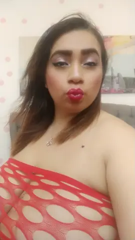 Woman in a red cutout mesh top making a playful pouty face in a bright indoor setting.