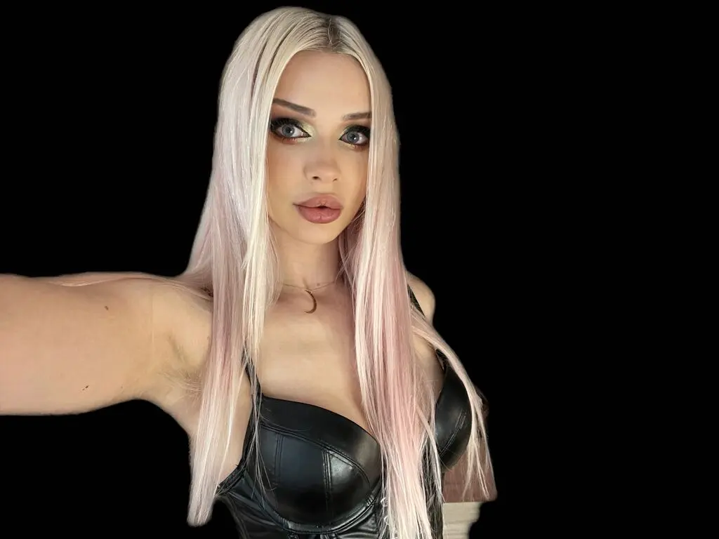 Blonde woman in a black leather corset top posing with glamorous makeup against a dark background.