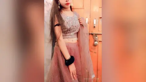 Young woman in elegant dusty rose sequined lehenga choli posing gracefully in a warm indoor setting.