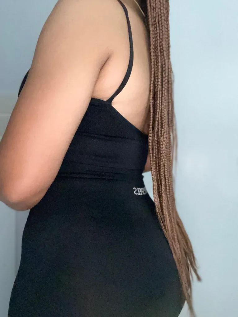 Goldie_xx poses in a black sports bra and matching leggings against a plain white wall.