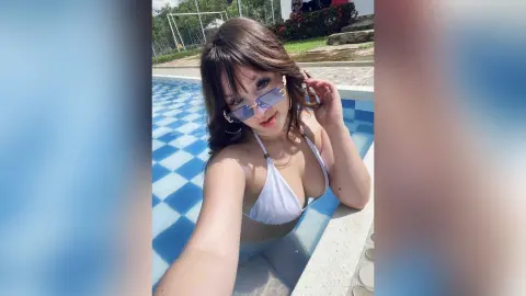 Young woman in white bikini sunglasses relaxing by a blue tiled swimming pool on a sunny summer day.