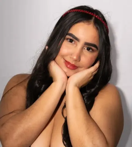 Smiling young woman with long dark hair and red headband posing against a white background.
