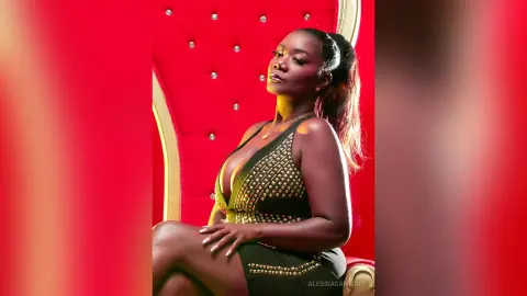 AlessiaSantoro — Elegant Black woman in a glamorous black sequined dress posing against a luxurious red tufted background.