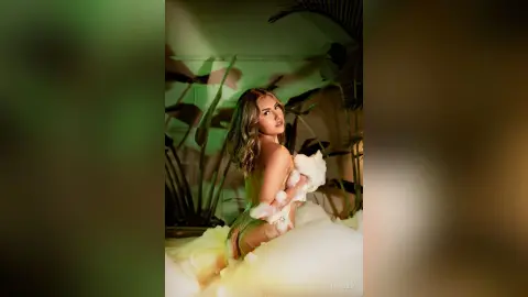 Glamorous woman in a white ruffled gown posing amidst tropical palm leaves in a moody, cinematic setting.