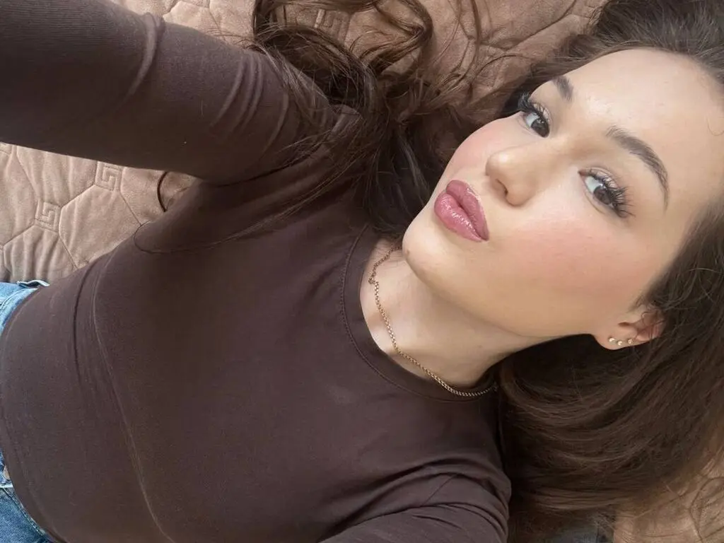 Young woman in a brown long-sleeve shirt relaxing on a quilted beige sofa with a calm expression.