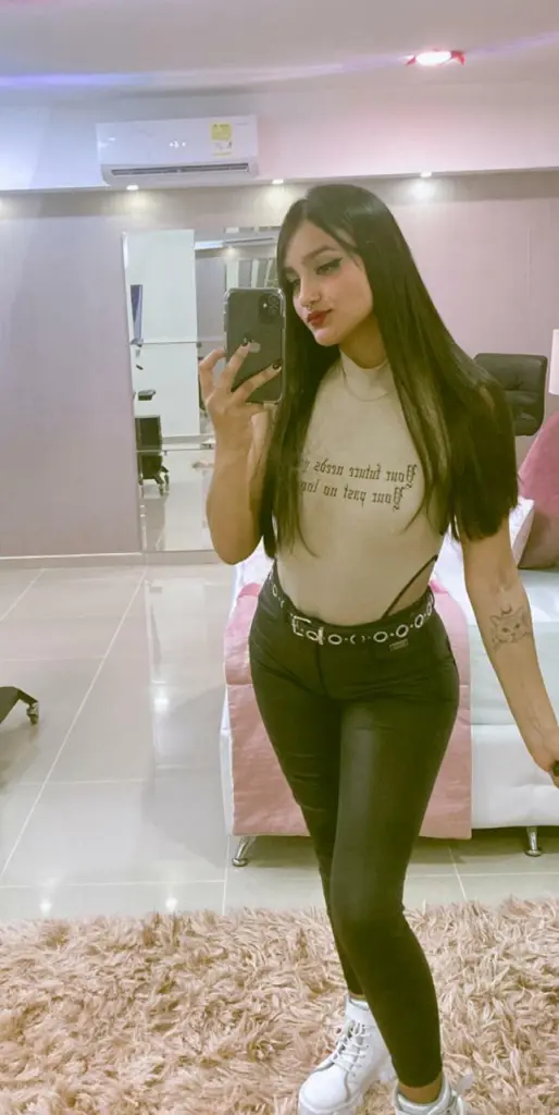 GabyDuraand poses with long dark hair and a black choker, wearing a black lace top while looking directly at the camera.