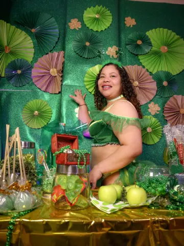 Smiling woman in green outfit at a festive St. Patrick's Day party with green decorations and candy jars.