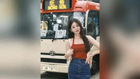 Stylish woman in a red tank top and denim skirt posing in front of a Mong Kok city bus.