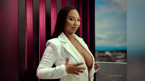 Elegant woman in a white blazer posing confidently against a modern architectural background.
