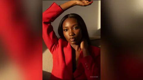 Elegant Black woman in a vibrant red blazer posing in warm, dramatic sunlight.