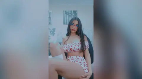 AmeliaStell poses in a red and white heart-patterned bra and matching bottoms while wearing glasses.