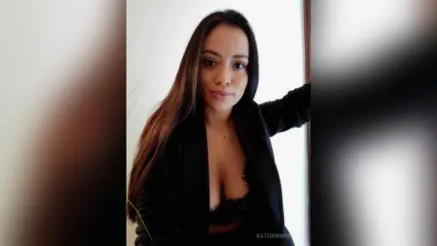 Elegant woman in a black blazer and lace top posing indoors with a confident mood.