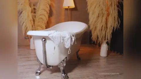 Elegant white clawfoot bathtub in a cozy bohemian bathroom setting with dried pampas grass decor.