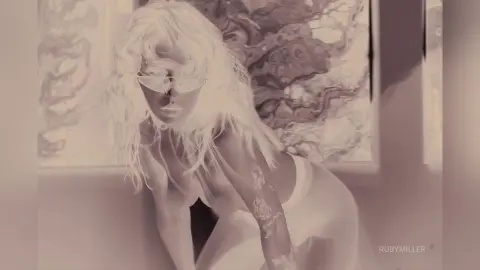 Blonde woman in white outfit posing against abstract art in a soft, dreamy monochromatic setting.