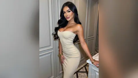 Glamorous woman in a tight cream strapless dress posing in an elegant indoor setting.