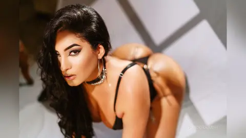 Glamorous woman in black lingerie posing in a bright studio setting with a moody, sensual aesthetic.