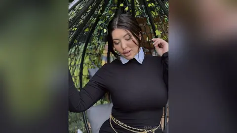 Curvy woman in a black long-sleeve turtleneck sitting in a garden egg chair with a relaxed mood.