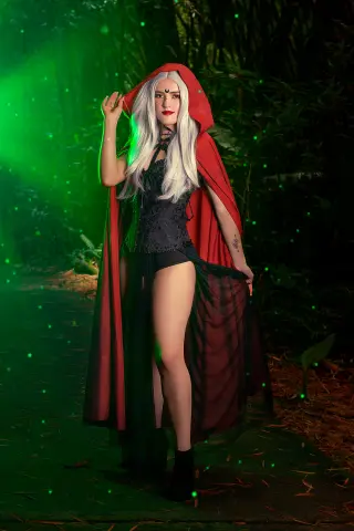AlicceGray wears a red hooded cape and black lace bodysuit while standing in a dark, green-lit forest setting with long silver hair.
