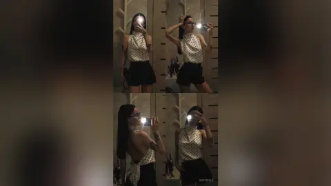 SofiMils poses for a mirror selfie wearing a white polka-dot halter top and black shorts, showing off her long dark hair and tattoos.