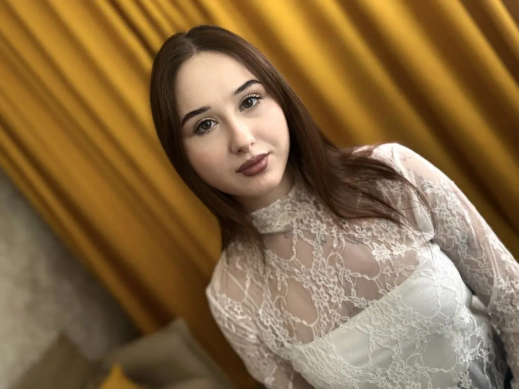 Young woman in a white lace blouse posing against elegant gold curtains in a soft, dreamy mood.