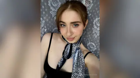 Young woman with brown hair wearing a black camisole and leopard print silk scarf against a floral backdrop.