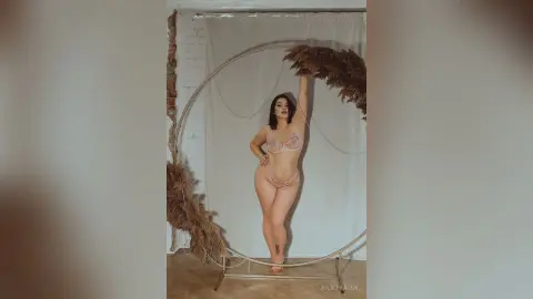 Elegant woman in lace lingerie posing in a minimalist studio with dried pampas grass decor.