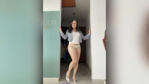 Young woman in a white tank top and beige briefs posing in a modern minimalist doorway.