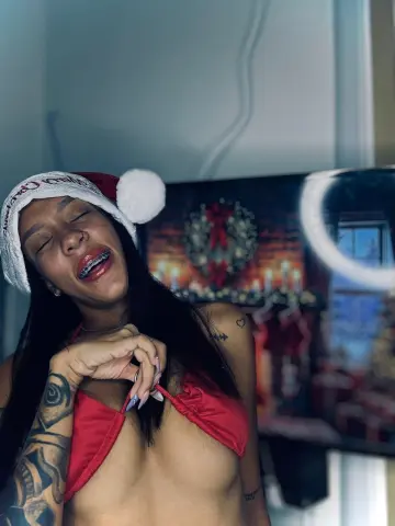 Smiling woman in a red bikini and Santa hat posing in a festive holiday setting.