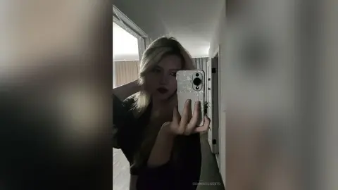 GemmaCiliberto takes a mirror selfie, showing her blonde hair and dark red lipstick while wearing a black top.
