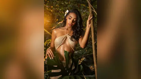 Beautiful woman in a gold crochet bikini posing in a lush tropical jungle during golden hour.