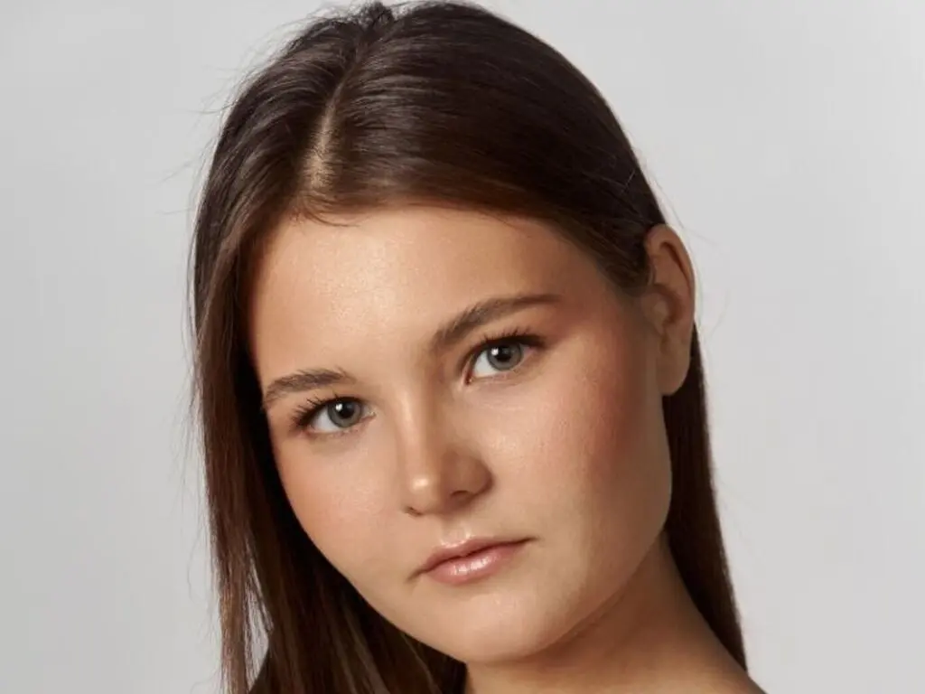 CaritaMattox looks into the camera with a soft expression in this close-up headshot against a plain background.
