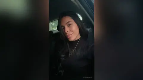 Smiling young woman in a black turtleneck sitting in a car during a moody evening.
