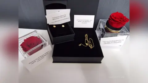 Elegant gold necklace and red rose gift set in luxury black velvet boxes for a romantic anniversary surprise.