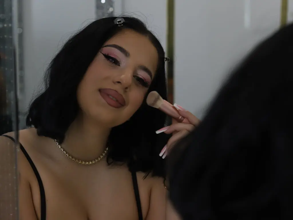 Young woman with pink eye makeup applying powder with a brush in a mirror for a soft beauty routine.